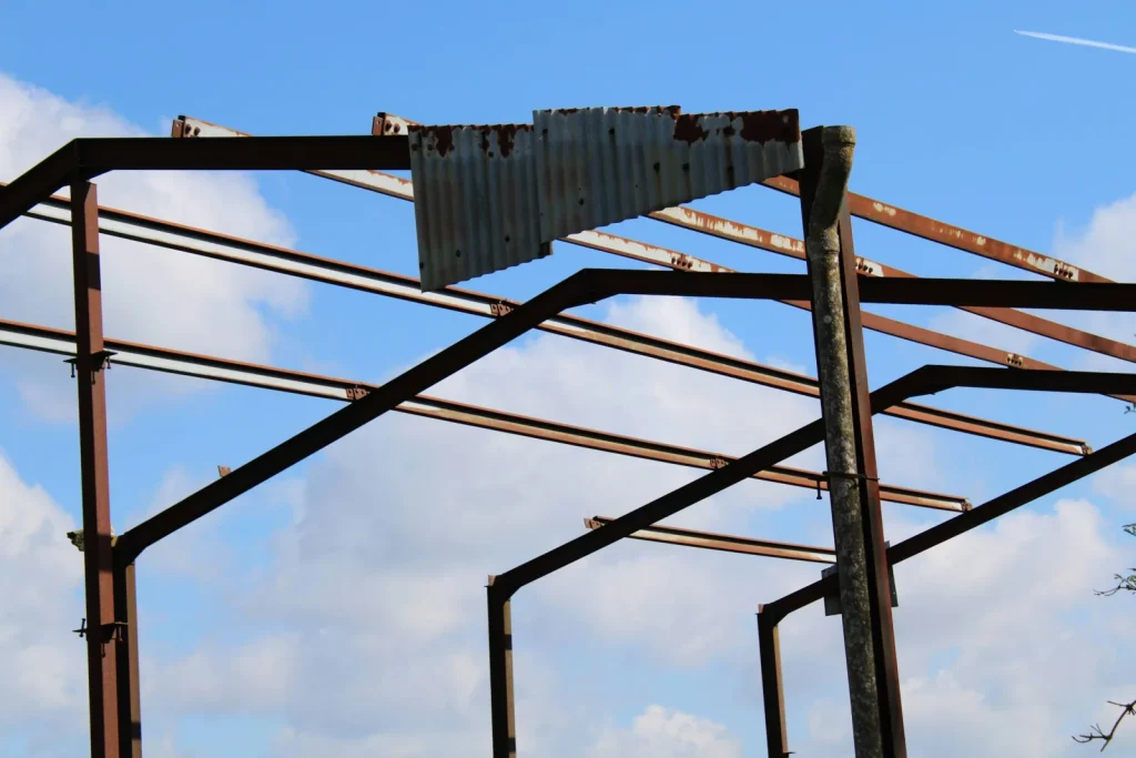 Estructura de acero oxidada de un galpón con una sola chapa en el techo