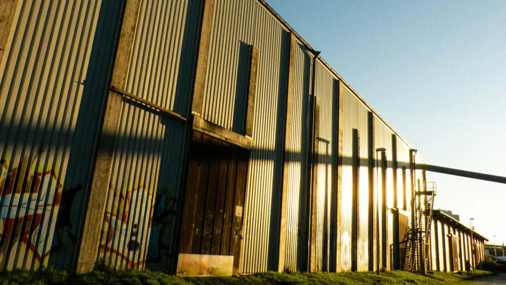 Fachada larga de un galpón industrial revestido en chapa con portón de madera
